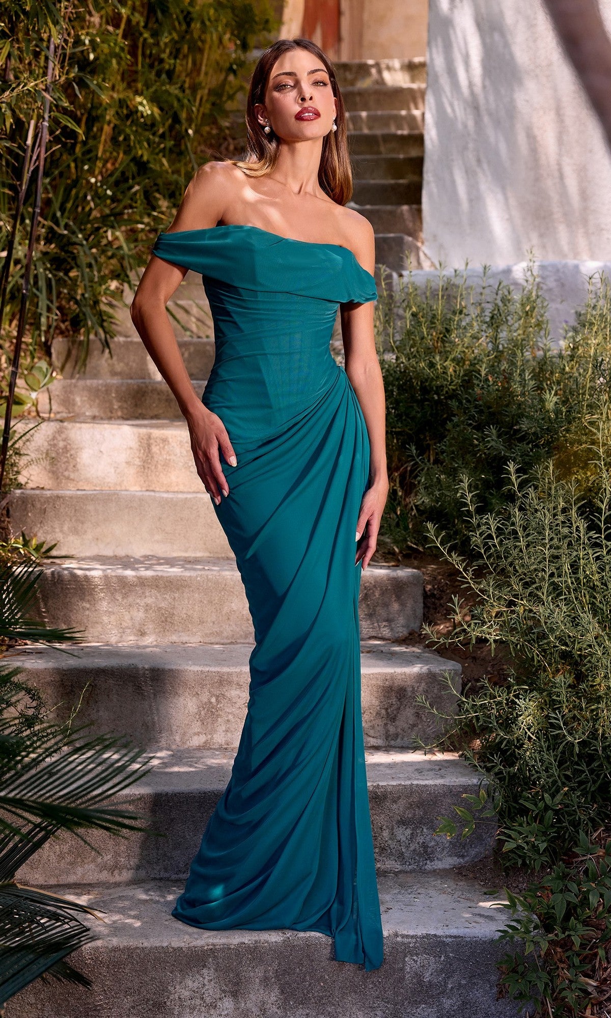 Woman outdoors on stone steps, wearing the Ladivine CD387 Multi-Way Lace-Up Long Prom Dress in fitted teal, featuring off-the-shoulder styling, draping detail, and a lace-up back.